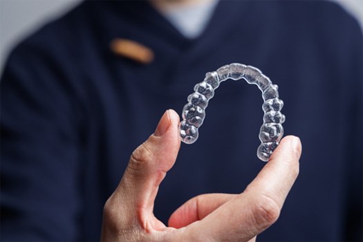 Dentist in navy blue shirt holding Invisalign tray