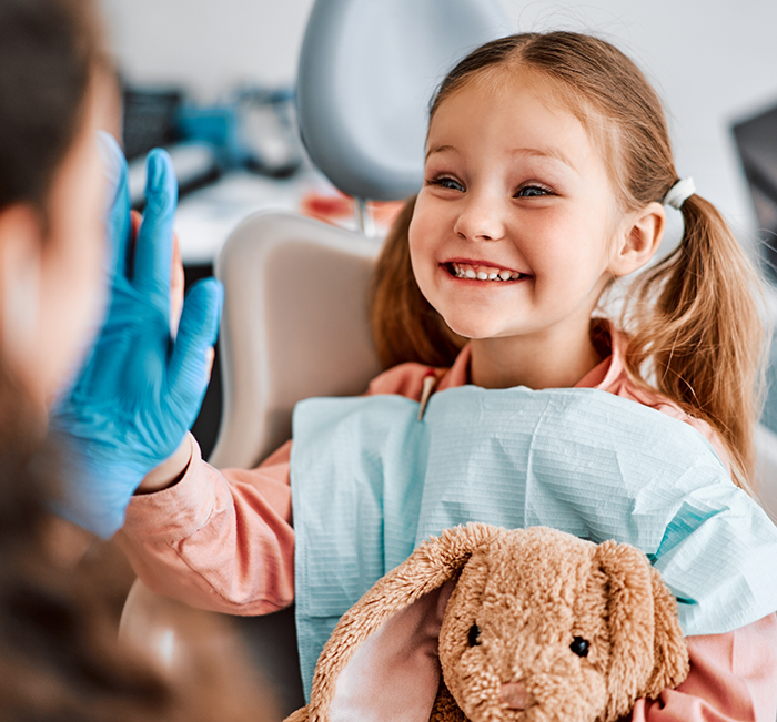 Young girl smiling and giving a high five to her childrens dentist in Brenham