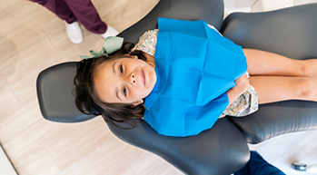 Young girl in dental chair looking up toward the camera