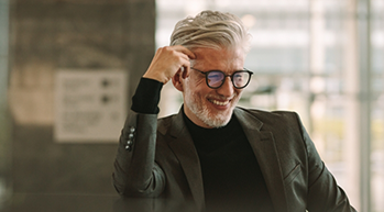 Smiling man with gray hair wearing a dark gray suit