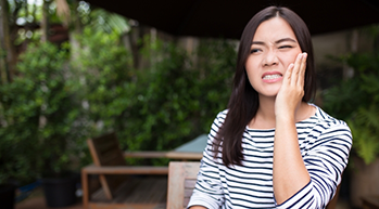 Young woman wincing in pain and holding her cheek