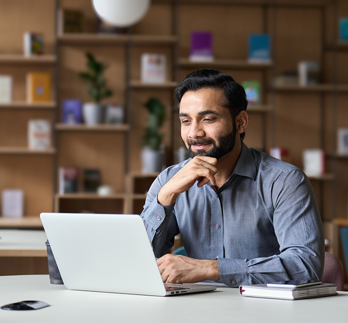 Man smiling while using his laptop at a table